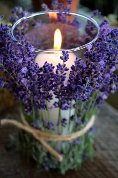 a candle that is sitting in some kind of vase with lavenders on it,