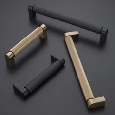 three different handles and pulls on a black surface with gold accents, including one in the middle