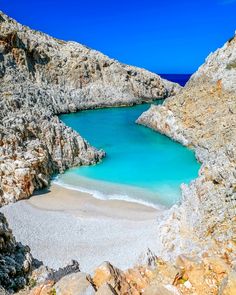 the water is blue and clear in this rocky beach area with white sand on the shore