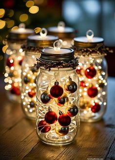 three mason jars filled with christmas ornaments on top of a wooden table covered in lights