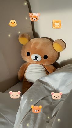 a brown teddy bear sitting on top of a bed next to pillows and sheets with face stickers