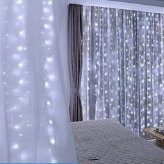 a bed room with a neatly made bed and lights on the curtained window sill