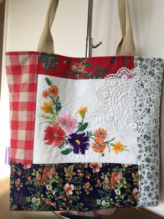 a handbag hanging from a hook on a wall with flowers and lace in it