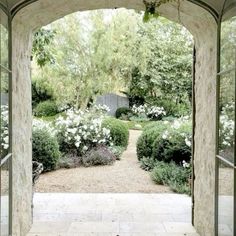 an archway leading into a garden with white flowers