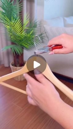 a person is cutting wood with scissors on a table in front of a potted plant