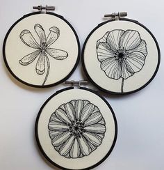 three black and white embroidered flowers are shown in this set of three hoop art pieces