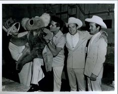 black and white photograph of four men in sailor hats holding up a stuffed animal while another man looks on