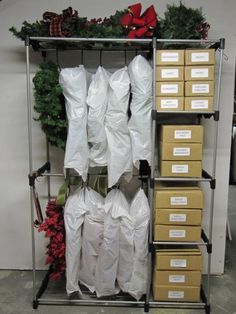 several boxes are stacked on top of each other in front of a metal rack filled with christmas wreaths