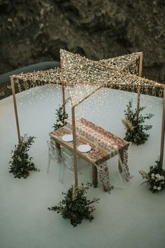 an outdoor table set up with lights and greenery on it for a winter wedding