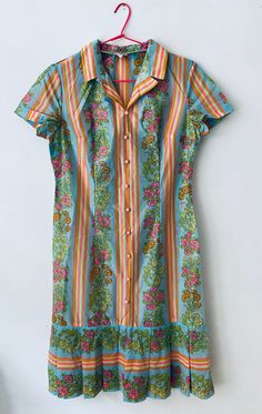 "This is such a cute vintage 80's short sleeved shirt dress with stripes and a lovely flower patterned panels in bright vivid colours of pink, yellow, orange and turquoise, the dress is made from a polyester fabric, it has baby pink buttons on the front and ruffle skirt. The dress is in excellent vintage condition. All garments are worn but in a good vintage condition, there may be small signs of wear or very minor flaws that are due to come with the items age but any more serious flaws that we find have been pictured. We do not except any returns for any sizing issues since we provide measurements, make sure to check them carefully and please ask for any extra information you might need that not be provided already, we measure our garment flat from side to side, armpit to armpit, hip to h Colorful Short Sleeve Dress With Vibrant Print, Colorful Vibrant Print Short Sleeve Dress, Vibrant Fitted Dress With Short Sleeves, Multicolor Cotton Dresses With Buttons, Spring Retro Print Short Sleeve Dresses, Retro Print Short Sleeve Dresses For Spring, Spring Retro Print Dresses With Short Sleeves, Summer Dress With Retro Print And Short Sleeves, Summer Dresses With Retro Print And Short Sleeves