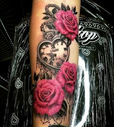 a woman's arm with pink roses and an old pocket watch tattoo on it