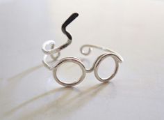 a pair of glasses made out of silver wire sitting on a table with one eye open and the other half closed