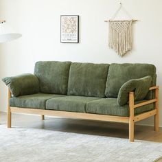 a green couch sitting on top of a wooden floor next to a white rug in a living room