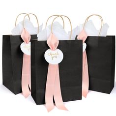 three black bags with pink ribbons and tags on them