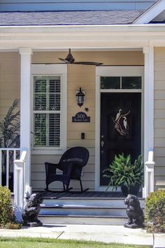 the front porch has two chairs on it and one is sitting in the grass next to the door