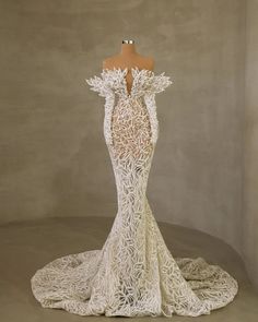 the back of a white wedding dress with intricate lace detailing and open shoulders, on a mannequin