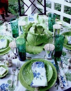 the table is set with green plates and silverware, napkins, and glasses