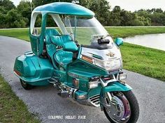 a blue motorcycle parked on the side of a road next to a lake and grass