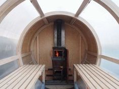 a room with benches and a wood stove in the center that looks like a tunnel