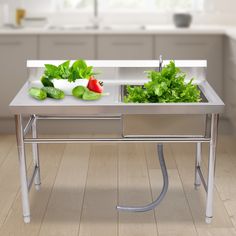 two stainless steel sinks with vegetables in them on a wooden floor next to a window