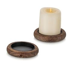 two candles sitting next to each other on top of a white surface with an oval candle holder in the middle