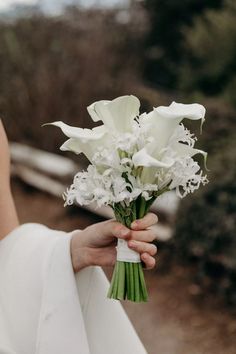 a woman holding a bouquet of white flowers