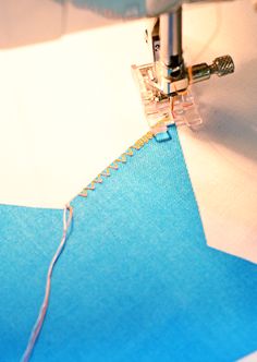 a close up of a sewing machine with blue fabric