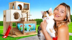 a woman holding a cat in front of a fish tank with a house on it