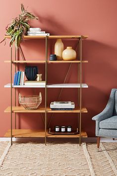 a living room with pink walls and a gold shelving unit filled with vases