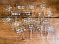 six clear plastic signs with words on them sitting on a wooden table next to each other