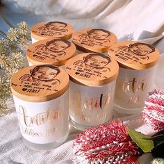 six jars with wooden lids are sitting on a table next to flowers and other decorations