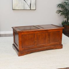 a large wooden trunk sitting on top of a rug in front of a white wall