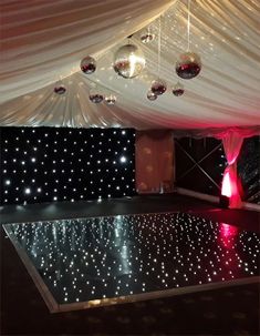 a dance floor with disco balls hanging from the ceiling and white drapes covering it