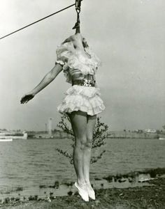 a woman hanging from a rope on top of a body of water