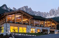 a large building with lots of windows in front of some mountains and lights at night