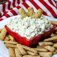 a red bowl filled with dip surrounded by crackers