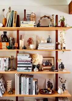 a bookshelf filled with lots of books and vases on top of it