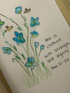 an open bible with blue flowers and the words she is clothed with strength