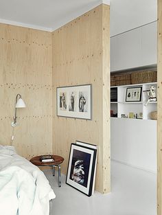 a bedroom with wood paneling and pictures on the wall, along with a small table