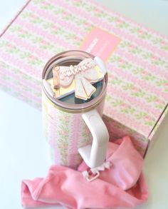 a cup with some clothes in it next to a pink napkin and a gift box