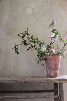 a pink vase filled with flowers sitting on top of a wooden table next to a wall