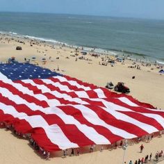 an american flag is being held up on the beach