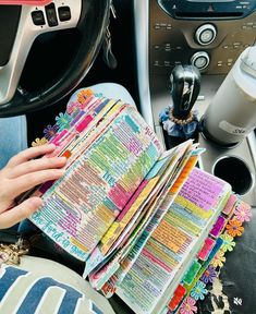 a person holding a book in their hand while sitting in the driver's seat of a car