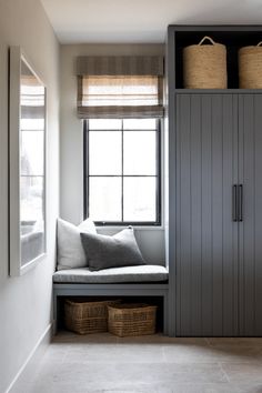 a window seat with two baskets on top of it in front of a bookcase