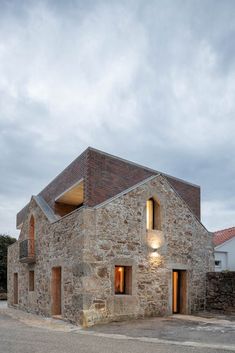 an old stone building with two windows on the front and one in the back that is lit up at night