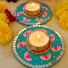 two plates with candles on them sitting next to flowers