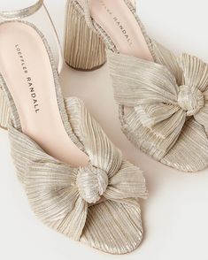 Heeled sandal in a shimmery off white/champagne platinum pleated lamé fabric topped with our signature pleated bow. Padded footbed with gold stamped logo. Open toe with adjustable buckle ankle strap. 3.5 inch heel. Bow Mules, Bow Sandals, Low Heel Sandals, Bow Heels, Shoe Inspo, Heeled Sandal, Loeffler Randall, New Sneakers, Leather Pieces