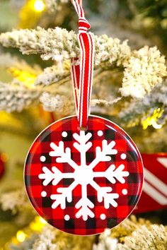 a red and black ornament hanging from a christmas tree with snowflakes on it