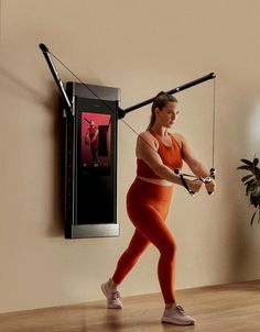 a woman in an orange sports bra and leggings is using a pull up bar