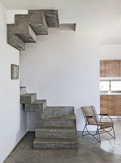 a chair sitting next to a set of stairs in a room with white walls and concrete floors